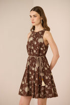 Woman wearing a brown floral dress against a beige background Calling June