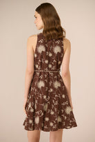 Woman wearing a brown floral dress against a beige background Calling June