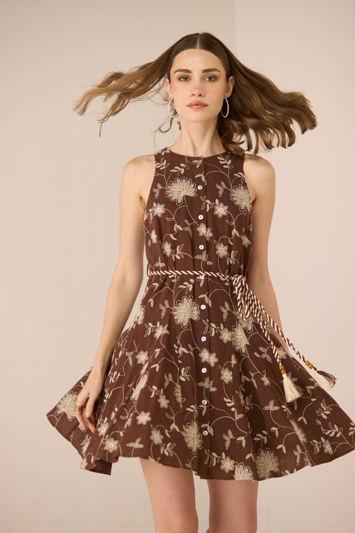 Woman wearing a brown floral dress against a beige background Calling June