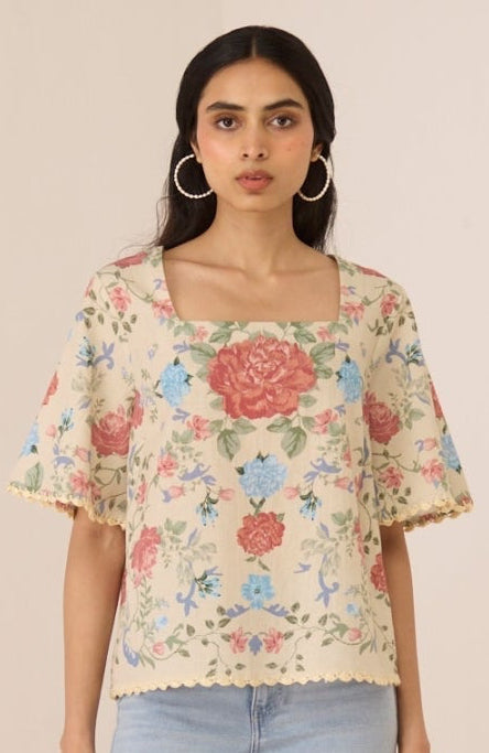 Woman wearing a floral blouse and light blue jeans on a beige background Calling June