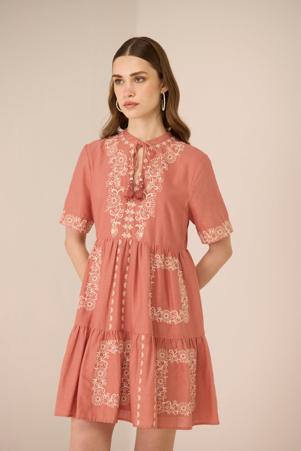 Woman wearing a pink dress with lace details on a beige background Calling June