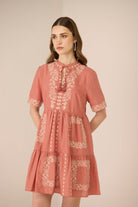 Woman wearing a pink dress with lace details on a beige background Calling June