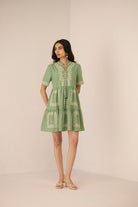 Woman wearing a green dress with white embroidery on a beige background Calling June