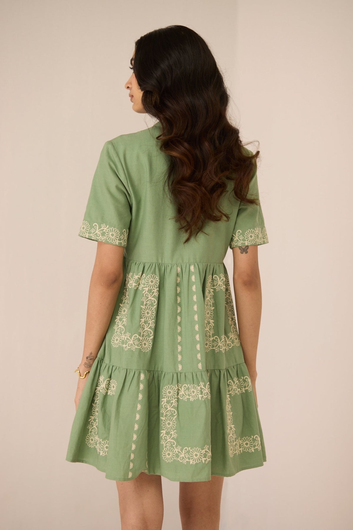 Woman wearing a green dress with embroidery details on a beige background Calling June