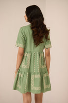 Woman wearing a green dress with embroidery details on a beige background Calling June