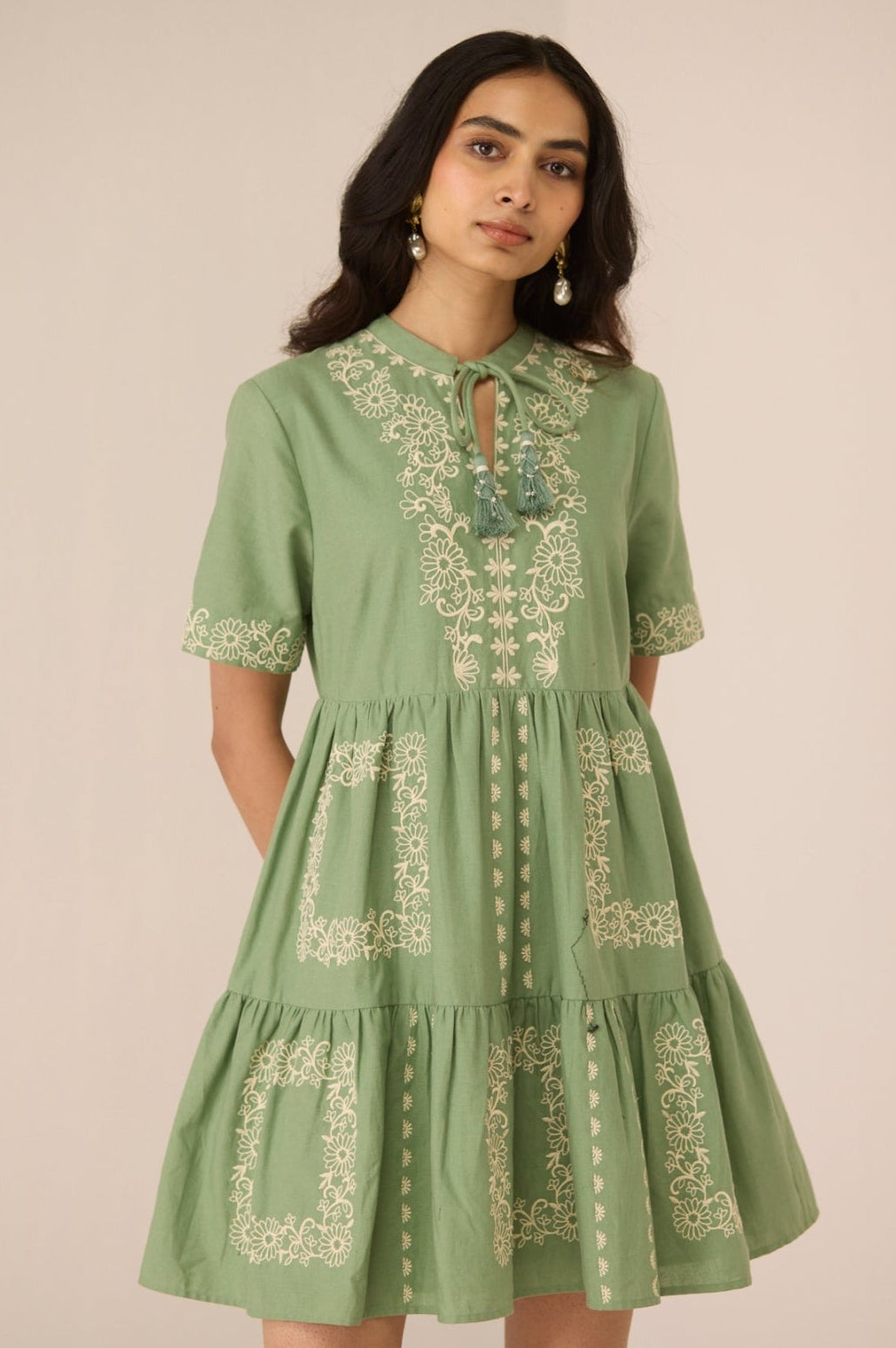 Woman wearing a green dress with embroidery on a beige background Calling June