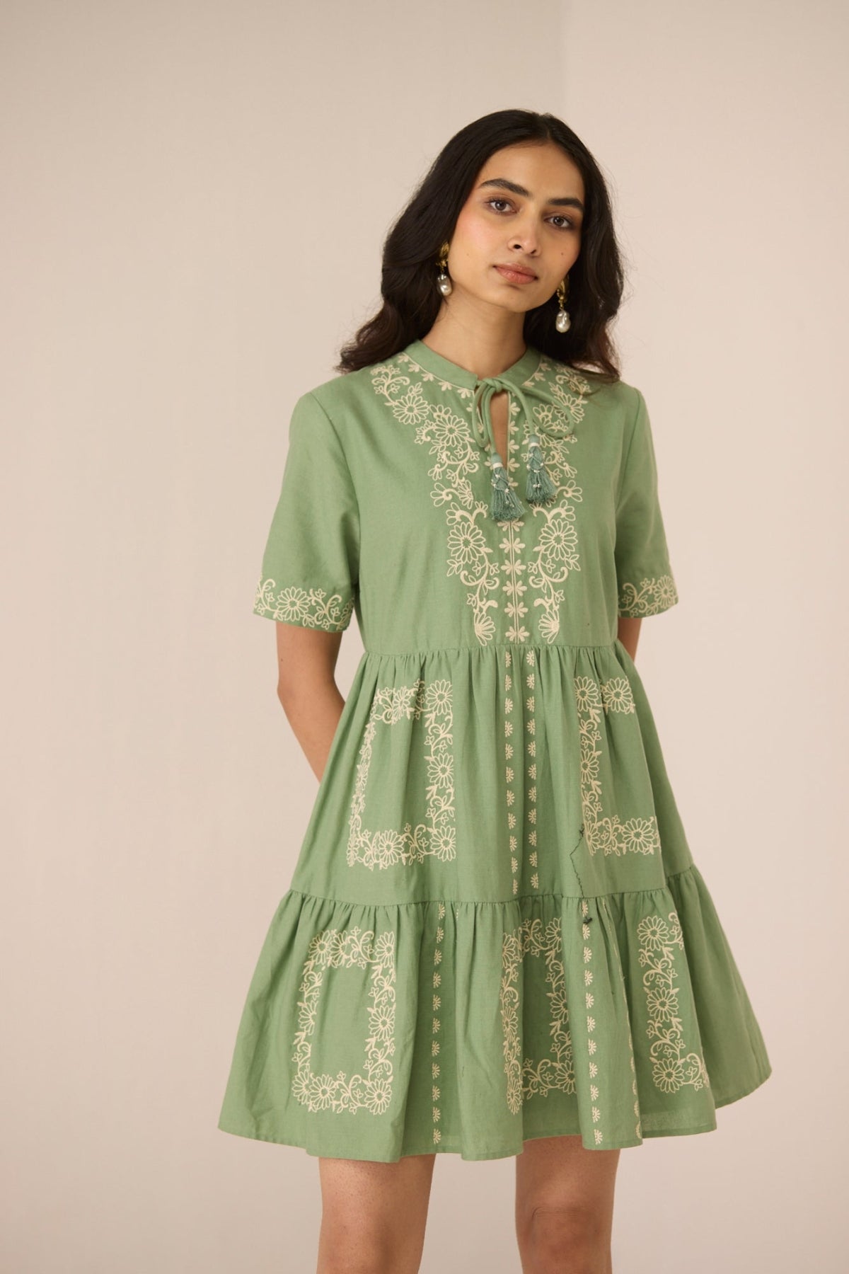 Woman wearing a green dress with embroidery on a beige background Calling June