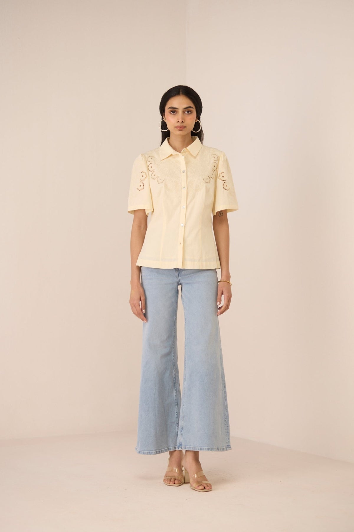 Woman wearing a light yellow blouse with short sleeves and light blue jeans on a beige background Calling June