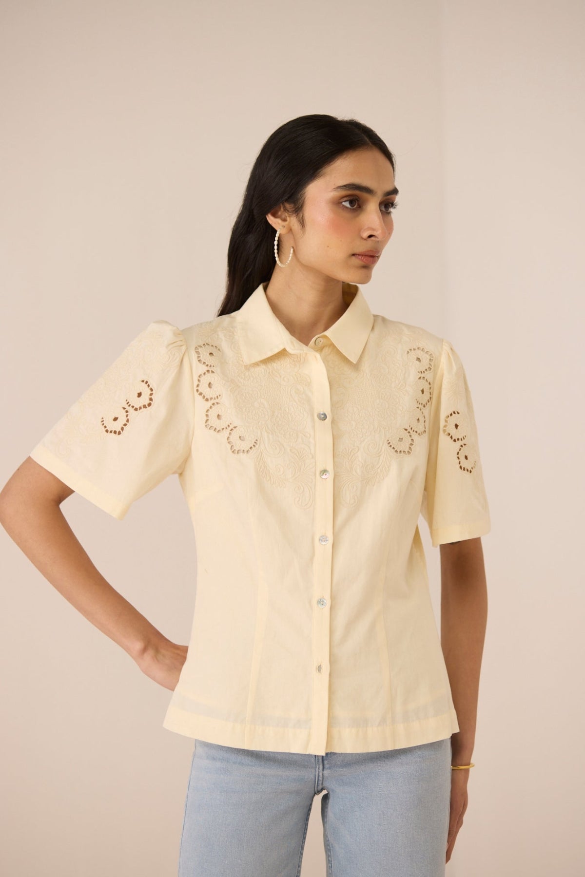 Woman wearing a beige embroidered shirt with short sleeves on a beige background Calling June