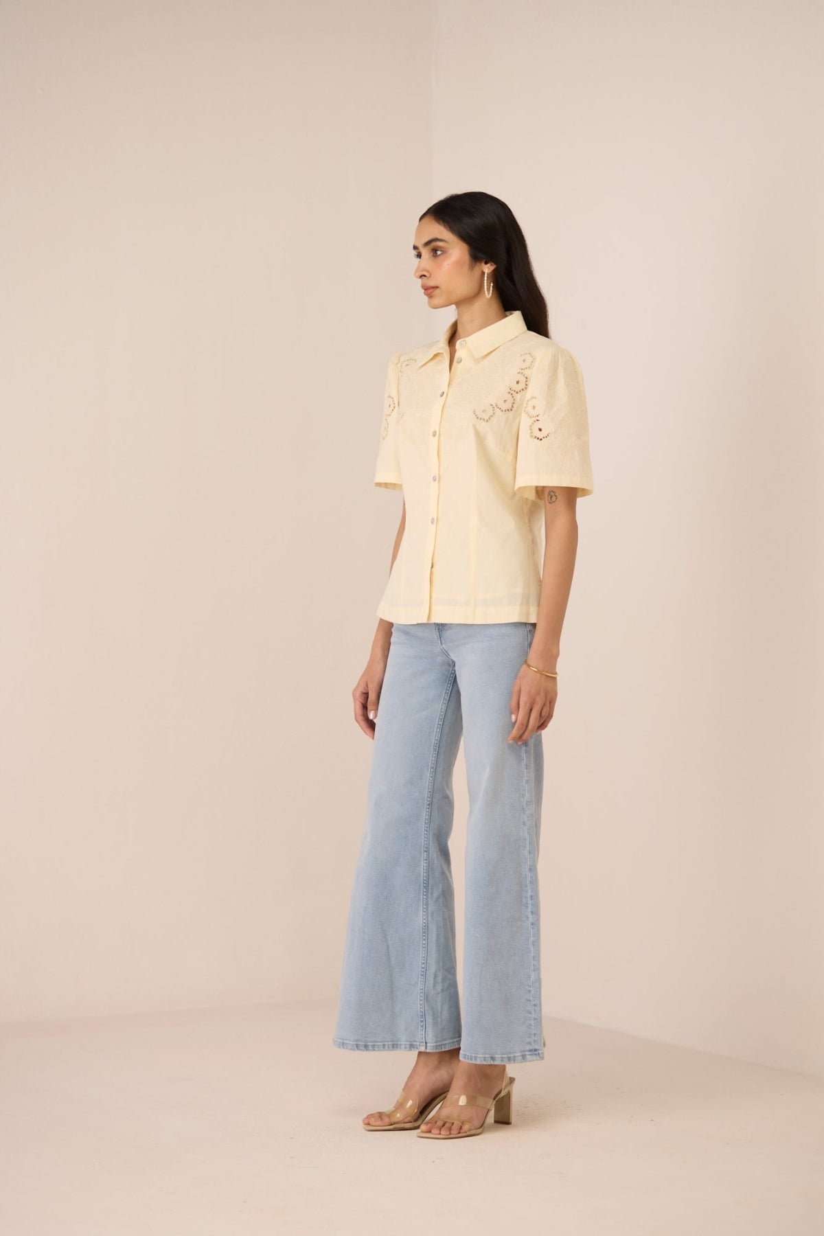 Woman wearing a light yellow blouse and light blue jeans on a beige background Calling June