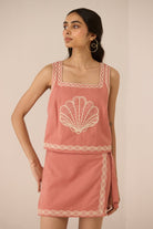 Woman wearing a pink dress with shell design on a beige background Calling June