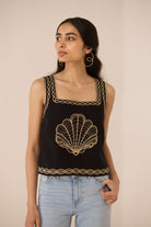 Woman wearing a black tank top with gold embroidery against a beige background Calling June