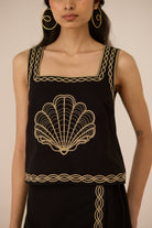 Black sleeveless top with gold embroidery on a plain background Calling June