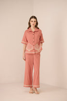 Woman wearing a pink outfit with shell patterns on a beige background Calling June