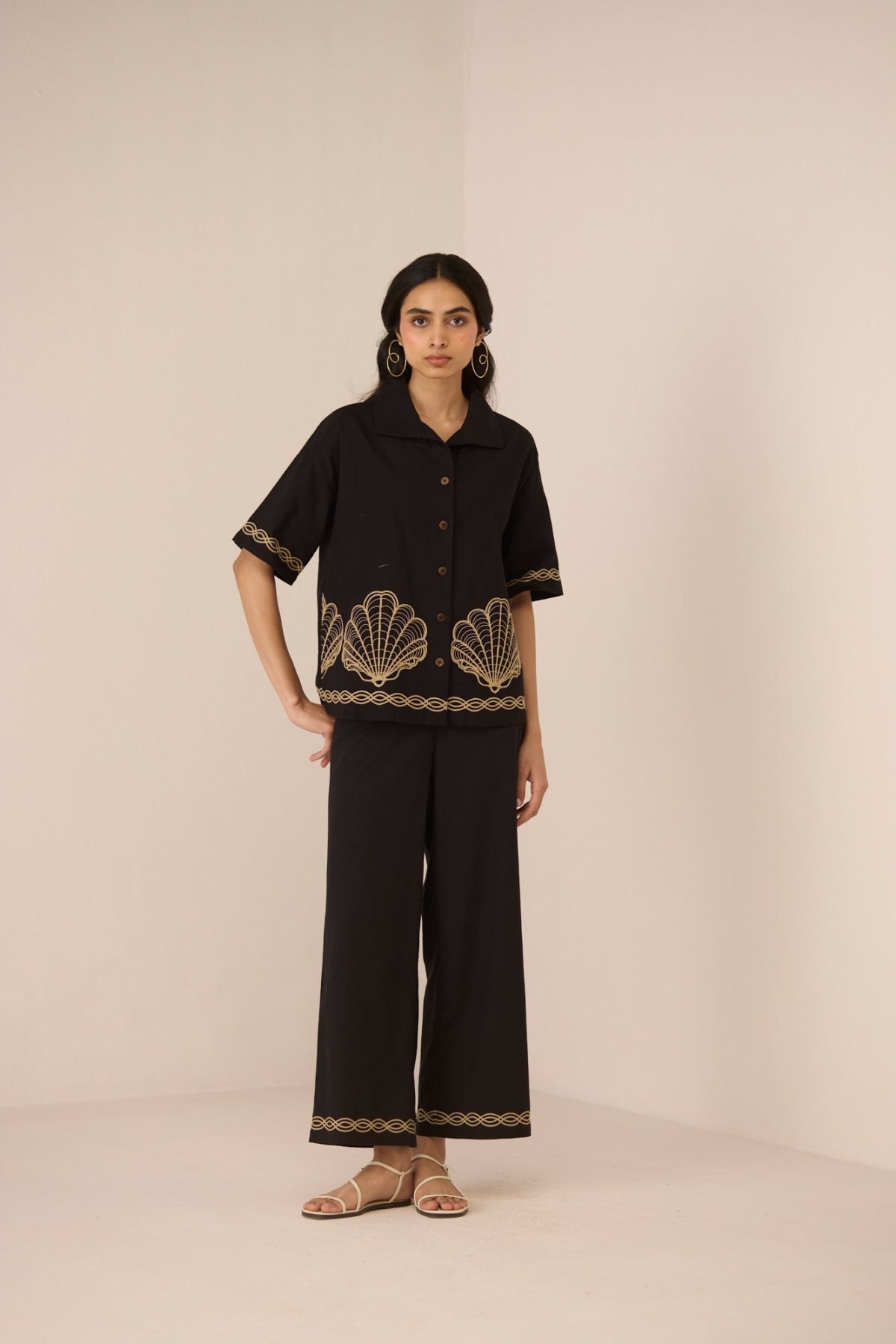 Woman wearing a black outfit with shell patterns on a beige background Calling June