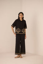 Woman wearing a black outfit with shell patterns on a beige background Calling June