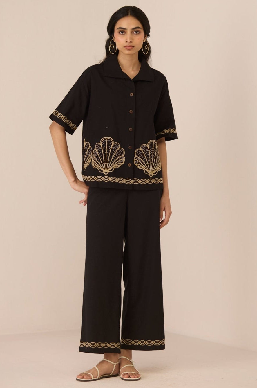 Woman wearing a black outfit with shell patterns on a beige background Calling June