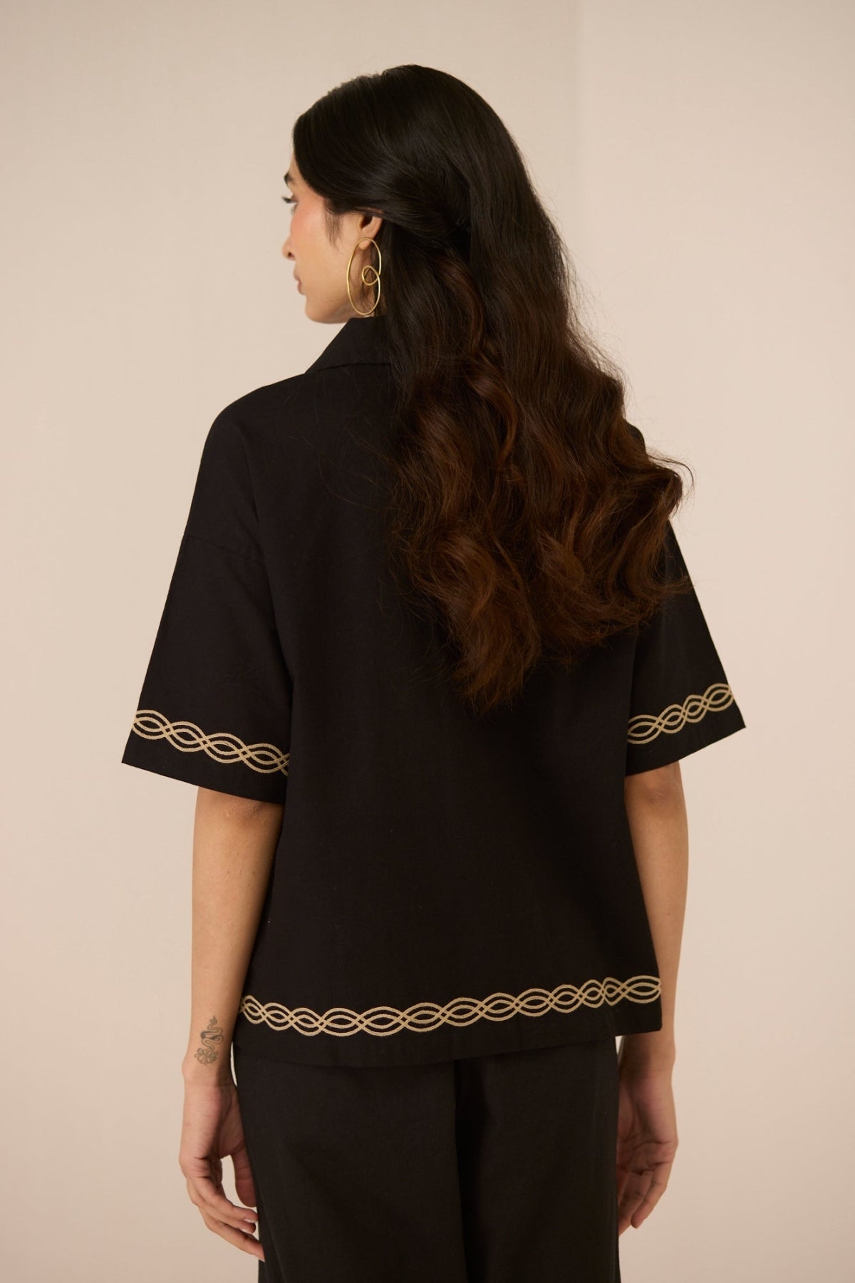 Woman wearing a black blouse with gold embroidery on a beige background Calling June