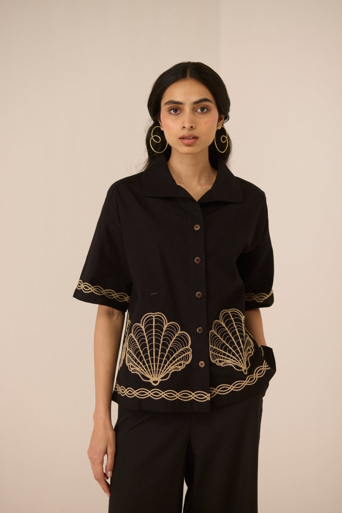 Woman wearing a black top with gold embroidery on a beige background Calling June