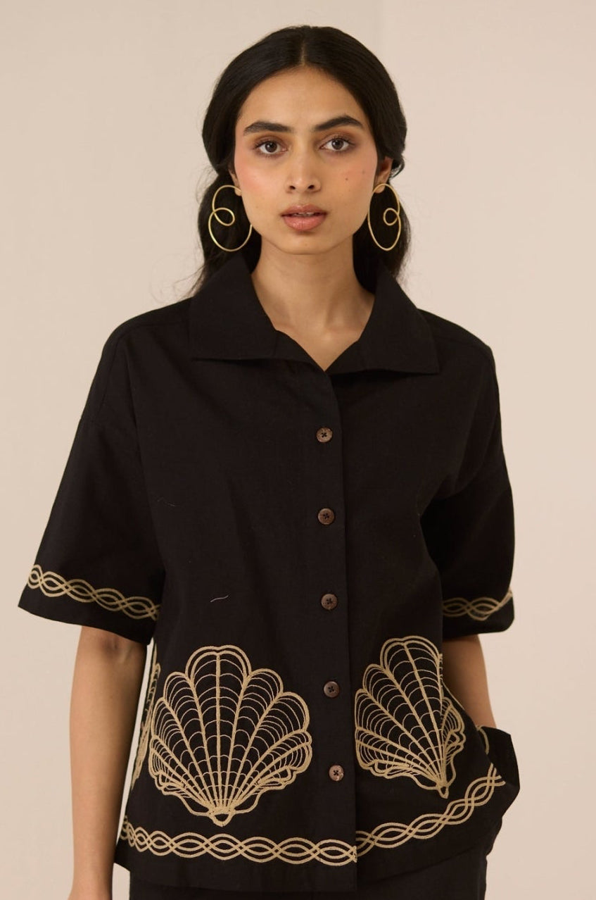 Woman wearing a black top with gold embroidery on a beige background Calling June
