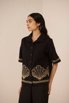 Woman wearing a black outfit with gold embroidery on a beige background Calling June