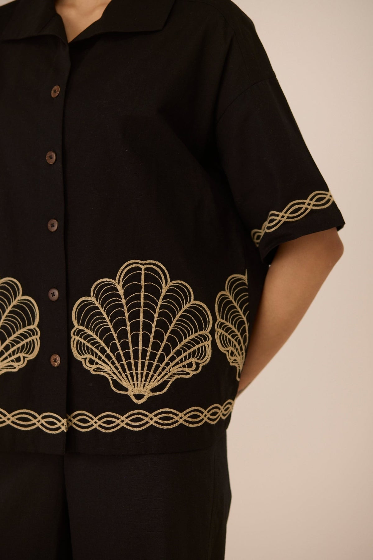 Black shirt with gold embroidery on a plain background Calling June