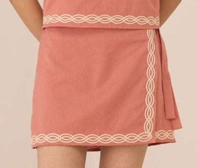 Woman wearing a pink dress with shell design on a beige background Calling June