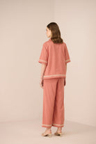 Woman wearing a pink pajama set with lace details on a beige background Calling June