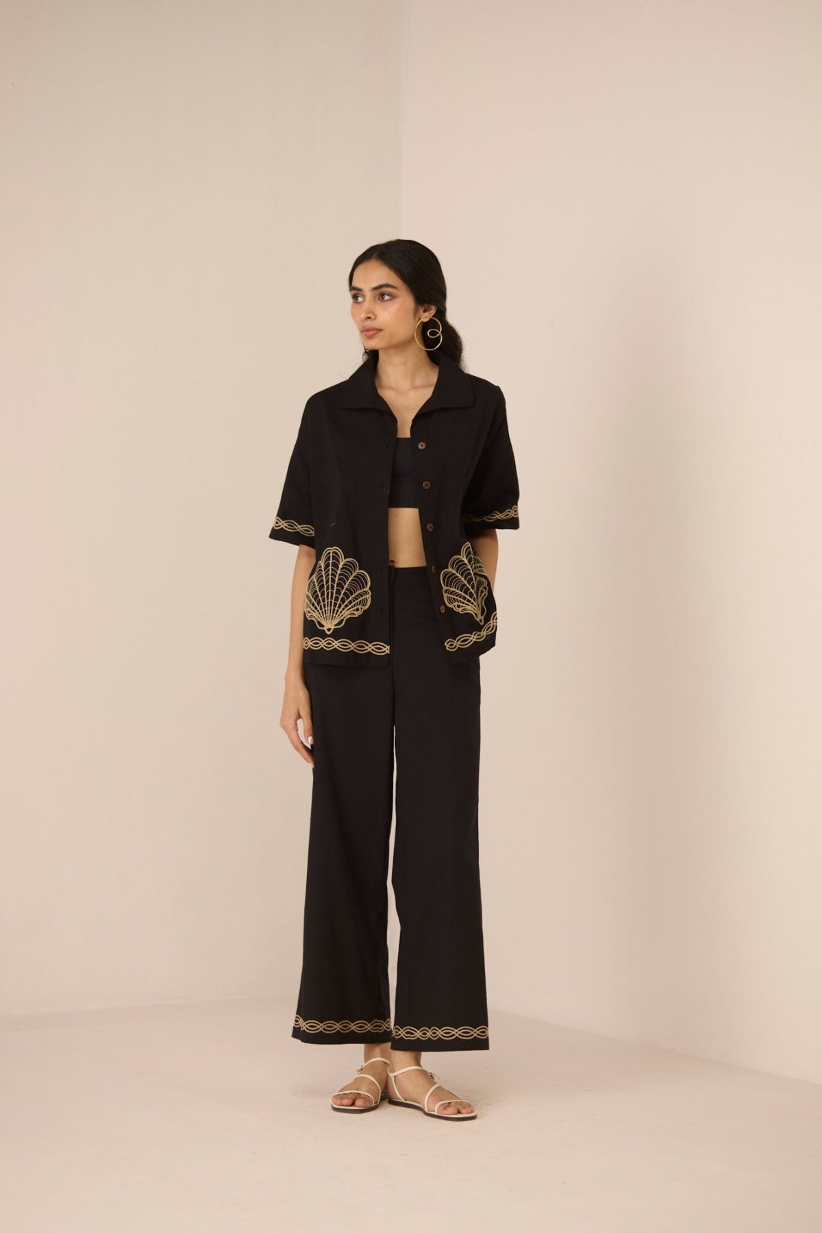 Woman wearing a black outfit with gold embroidery on a beige background Calling June