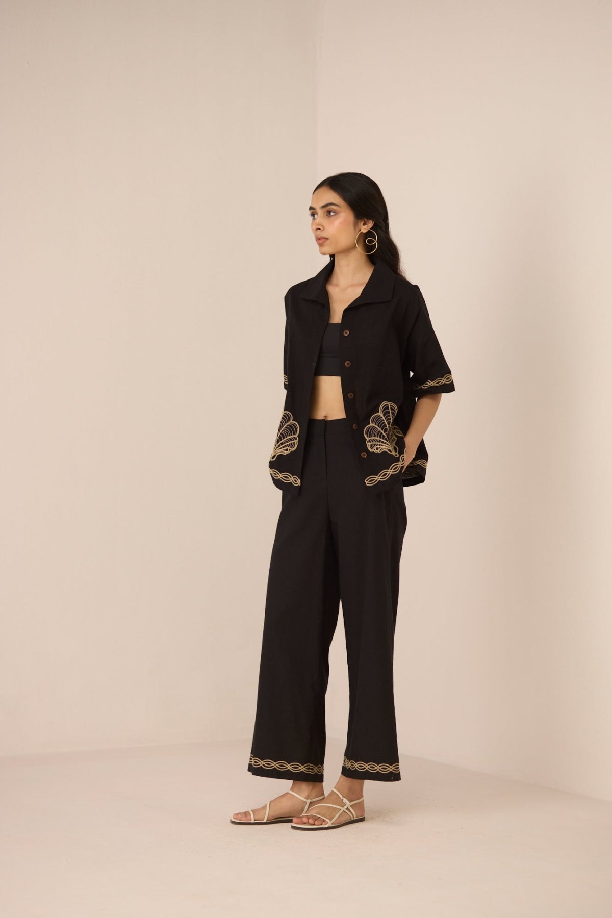 Woman wearing a black outfit with gold embroidery on a beige background Calling June