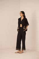 Woman wearing a black outfit with gold embroidery on a beige background Calling June