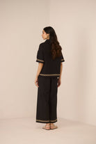 Woman wearing a black outfit with lace details on a beige background Calling June