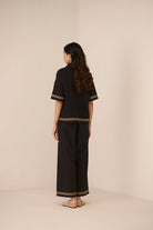 Woman wearing a black outfit with lace details on a beige background Calling June