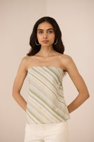 Woman wearing a strapless top with green and white stripes against a beige background Calling June