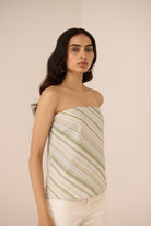 Woman wearing a strapless outfit with a striped top against a beige background Calling June