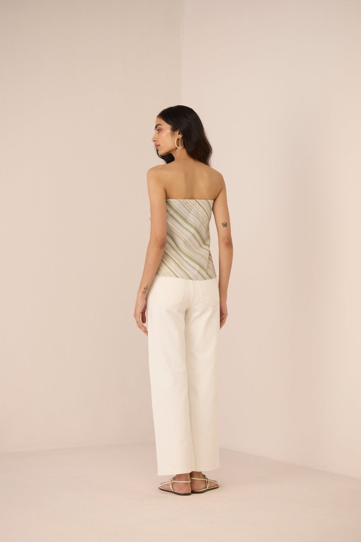 Woman wearing a strapless top and wide-leg pants on a beige background Calling June