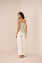 Woman wearing a strapless top and wide-leg pants on a beige background Calling June