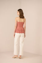 Woman wearing a pink strapless top and white pants on a beige background Calling June