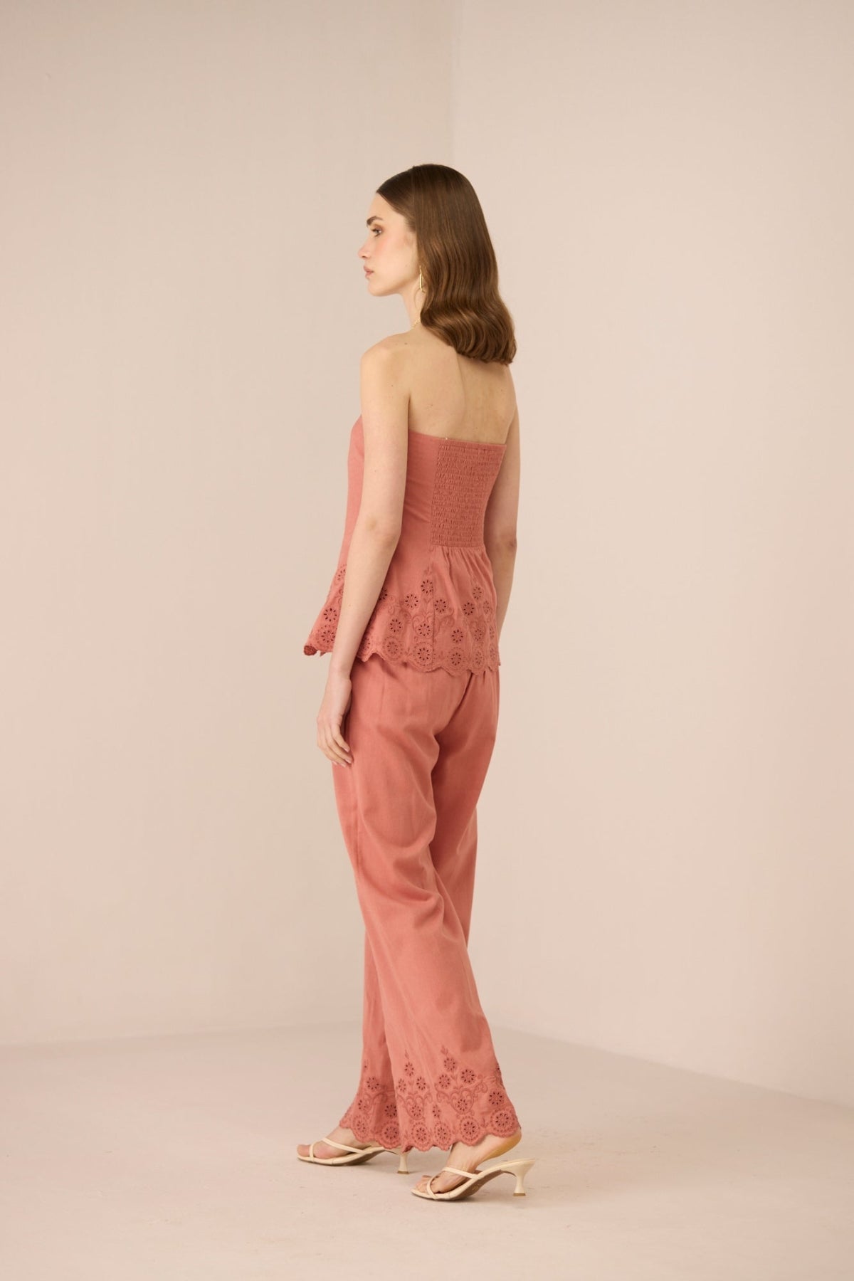 Woman wearing a pink lace outfit on a beige background Calling June