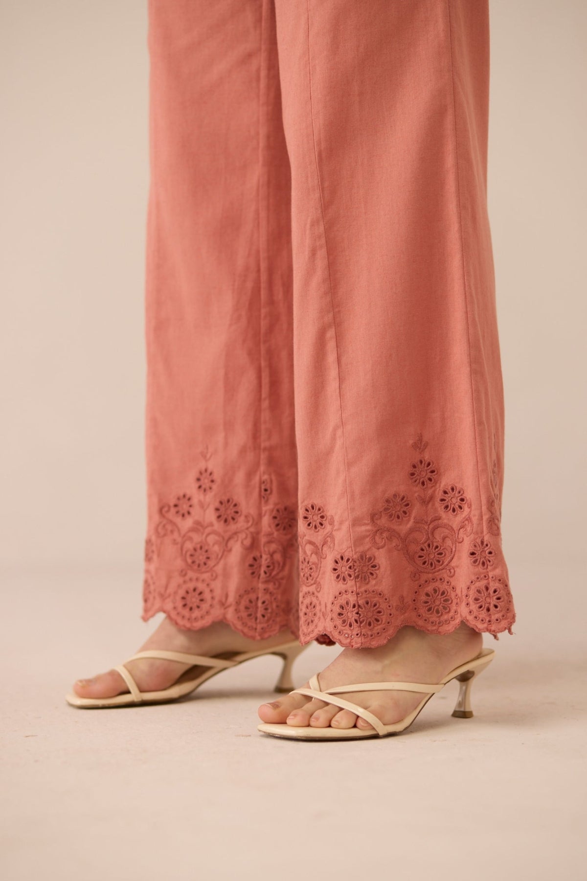 Coral pants with lace detailing and beige sandals on a beige background Calling June