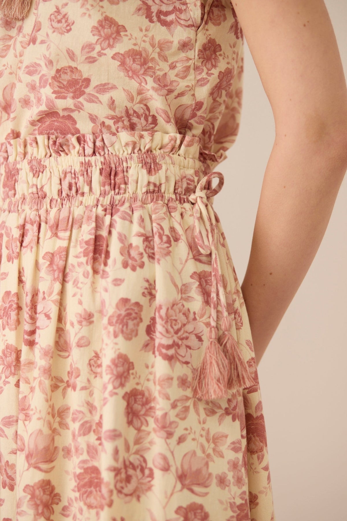 Close-up of a floral dress with pink flowers on a beige background Calling June