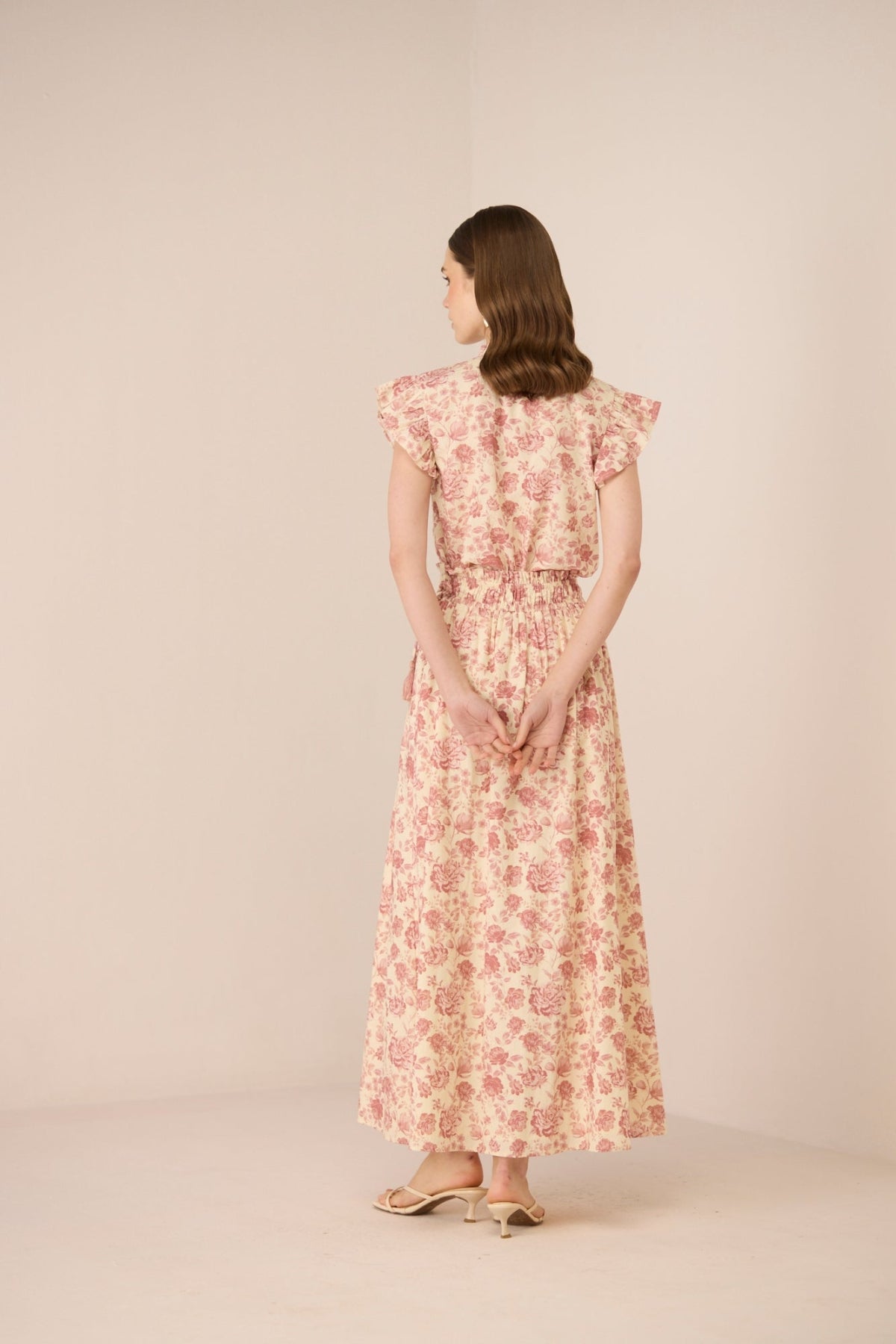 Woman wearing a floral dress against a plain background Calling June