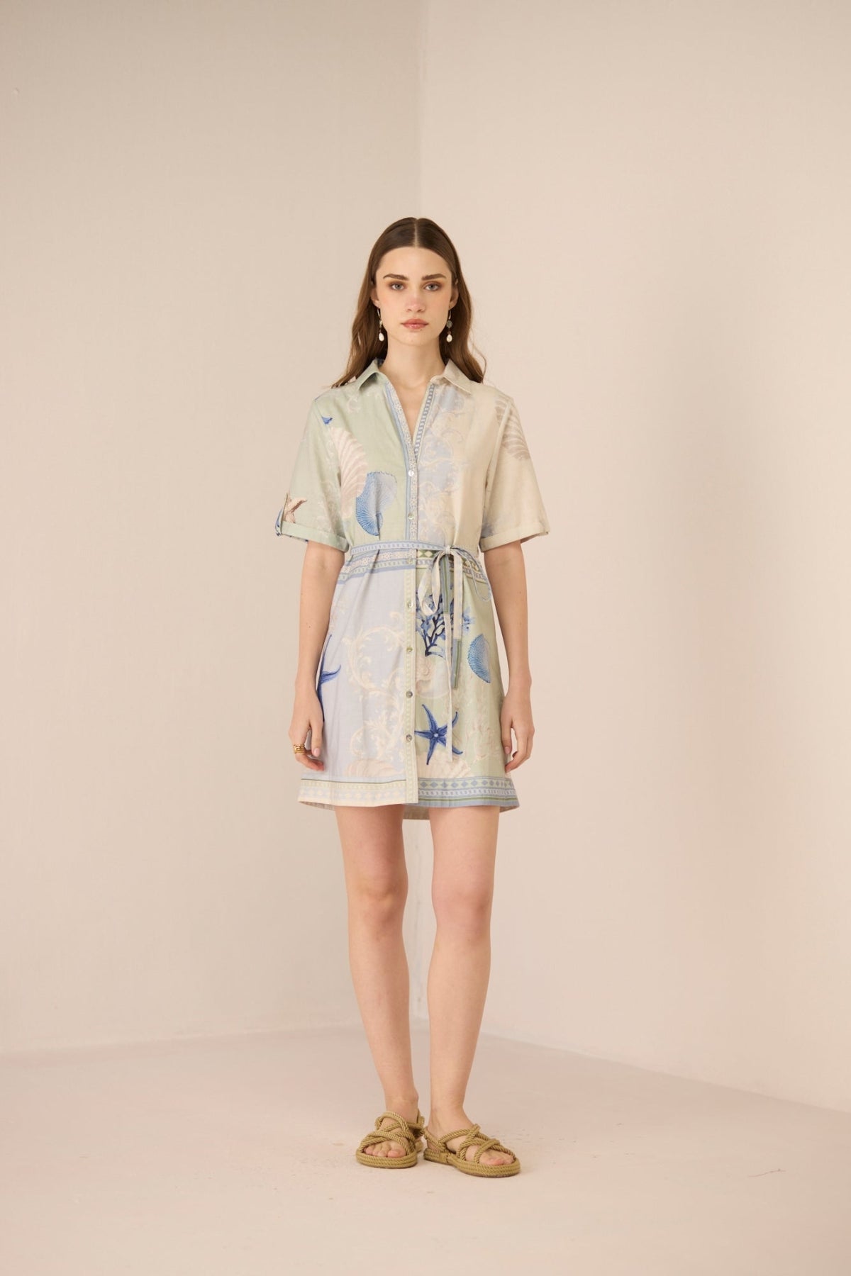 Woman wearing a light-colored dress with a pattern on a beige background Calling June