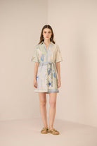 Woman wearing a light-colored dress with a pattern on a beige background Calling June