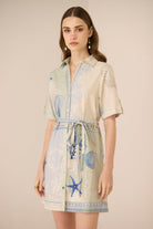 Woman wearing a short-sleeve dress with blue sea-themed patterns on a beige background Calling June