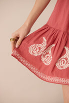 Red dress with white embroidery on a beige background Calling June