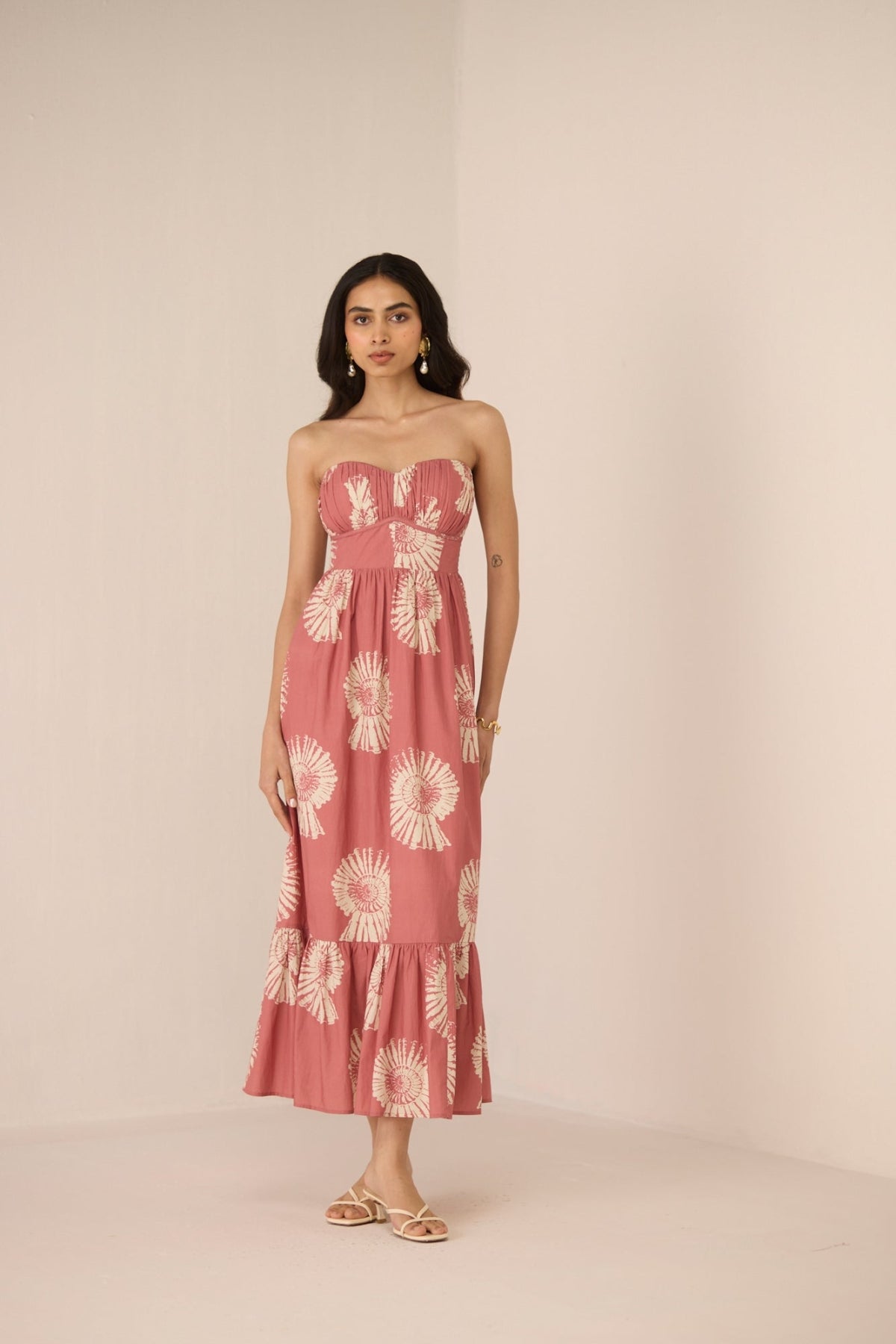 Woman wearing a pink strapless dress with floral pattern on a beige background Calling June