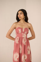 Woman wearing a strapless pink dress with floral patterns on a beige background Calling June