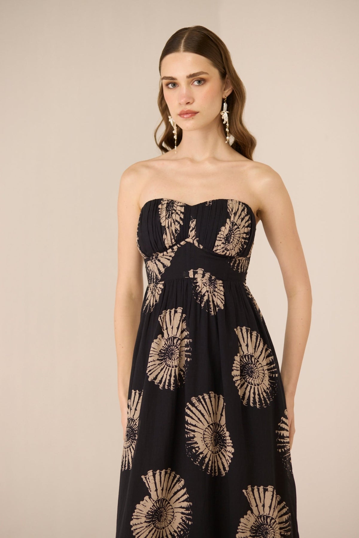 Woman wearing a strapless dress with sunflower pattern on a beige background Calling June