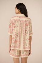 Woman wearing a floral patterned outfit on a beige background Calling June